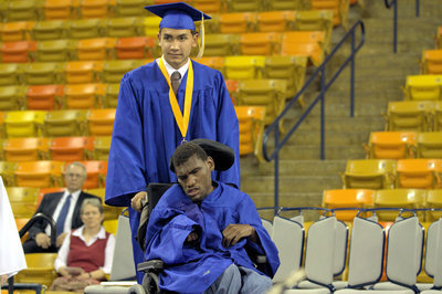 Image: Student Body President Joshua Salisbury assists Isaac McMahon during the announcement of the graduates