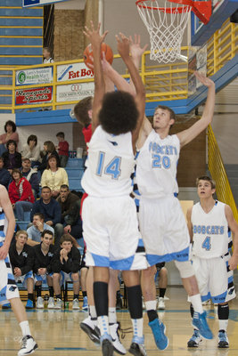 Image: Jalen Moore (14) and John Demueetz (20) defend under the basket, while Riley Knowles (4) looks on.