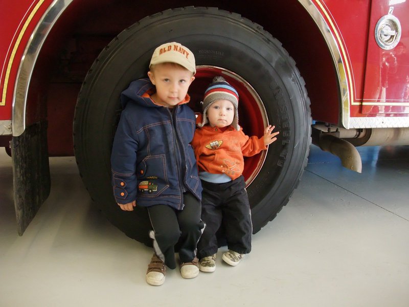 Image: Big truck — Tanner Hall who is almost four-years-old sits with his little brother Landon in the wheel of the fire engine.